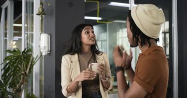 Muhtelif iş arkadaşları ofiste kahve fincanı ve kahkahalarla hareket ederek fikir kıvılcımına tepki veriyorlar. İşbirliği, iletişim, takım çalışması, modernlik, gayri resmi, enerjik, enerjik