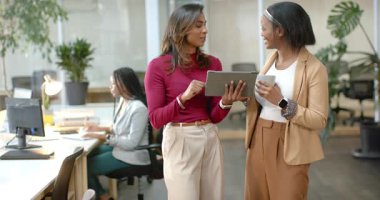 Kahve fincanı Afro-Amerikan iş arkadaşlarının geldiğini, tableti gösterdiğini ve ofiste açıkladığını fark ettim. İşbirliği, takım çalışması, profesyonel, iletişim, teknoloji, tartışma, iş