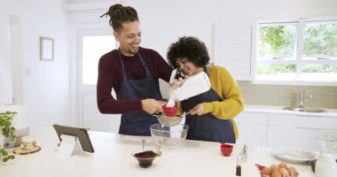 Kadın un kavanozunu kaptıktan sonra, mutfakta hamuru hazırlayan çift kase içinde un elliyor. Aşçılık, işbirliği, aşçılık, yerli, minimalist, sıcak, neşeli