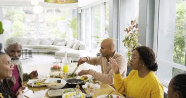 Çok nesilli bir aile rosto yapıyor, salata ve mısır servis ediyor, yemek masasına meyve suyu koyuyor. Aile, toplanma, kutlama, mutfak, birliktelik, yaşam tarzı, modern