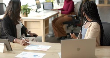 İş kıyafetleri içindeki çeşitli iş arkadaşları, çalışma masasındaki çizelgeleri işaretlerken yükselen meslektaşlarına göz gezdiriyorlar. İşbirliği, takım çalışması, ofis, profesyonel, iletişim, analitik, çağdaş