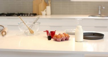 Kamera, mutfak tezgahını tarıyor ve pişirme malzemelerini karıştırmaya hazır gösteriyor. Pişirme, aşçılık, malzemeler, hazırlık, modern, minimalist, taze