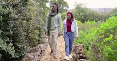 Çalıları işaret eden, farklı yollarda yürüyen çift ve keşif için bitkileri inceleyen. Doğa, keşif, macera, yeşillik, eğlence, biyolojik çeşitlilik, dinginlik