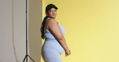 Dişi model gövde hareketi ve stüdyo ışığı standında sarı arkaplan ile siyah kapağı ayarlamak. Moda, portre, minimalizm, fitness, yaşam tarzı, dinamik, stüdyo