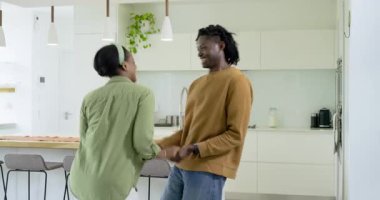 Tutucu eller, Afrika kökenli Amerikalı çift aşkla ahşap mutfak adasında dans edip sallanıyorlar. Romantizm, samimiyet, bağlantı, hareket, uyum, şefkat, neşe