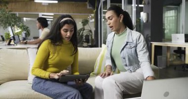 Meslektaşlarını tespit eden ve proje verilerini ofis salonundaki tablet ve dizüstü bilgisayardan izleyen çeşitli iş arkadaşları. İşbirliği, takım çalışması, iletişim, modern, profesyonel, yenilik, tartışma