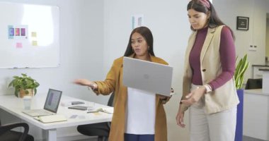 Ofisteki çeşitli bayan meslektaşlar dizüstü bilgisayarlarıyla masaya doğru yürüyorlar, kurgu için ekranı inceliyorlar. İşbirliği, takım çalışması, yenilik, profesyonellik, modern, teknoloji, iletişim