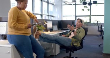 Çeşitli iş arkadaşları açık planlı ofiste verileri tartışırken proje detaylarını tablette gözden geçiriyorlar. İşbirliği, takım çalışması, dijital, modern, profesyonel, işyeri, iletişim