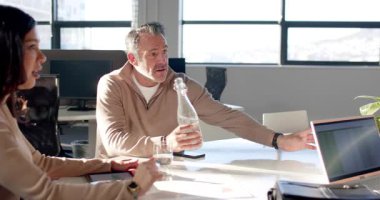 İspanyol kadın ofiste sohbete başlıyor, kıdemli adam iş arkadaşına eğildiği için su dolduruyor. İşbirliği, takım çalışması, modern, profesyonel, iletişim, çeşitlilik, üretkenlik