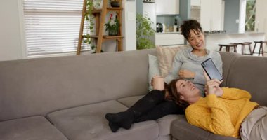 Akıllı telefon seçmek, çeşitli bayan arkadaşlar gri koltukta ekrana bakmak için eğilmek, kopyalama alanı. Samimiyet, dostluk, rahatlama, ev ortamı, günlük yaşam tarzı, samimiyet, dostluk.