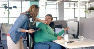 Muhtelif iş arkadaşları çalışma masasındaki çizelgeyi inceliyor, meslektaşları grafiğe işaret ediyor, beşlik çakıyor. İşbirliği, takım çalışması, profesyonel, modern, üretkenlik, iletişim, işyeri