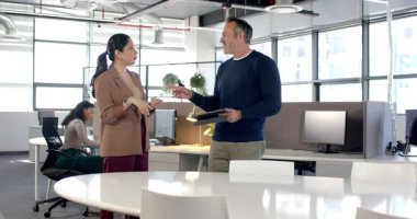 Çeşitli iş arkadaşları toplantı masasında danışman tıkırtısı tableti olarak sayıyor ve her ikisi de gülüyor. İşbirliği, iletişim, takım çalışması, profesyonellik, modern iş, etkileşim