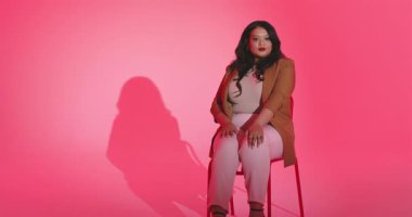 Yetişkin bir kadın kamerayı kapatıyor, stüdyo portresi için sandalyeye oturtuyor. Profesyonel, portre, minimalist, kadınsı, zarafet, güven, güzellik