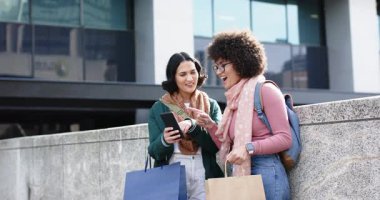 Plaza 'da bariyerlere yaslanan çeşitli bayan arkadaşlar, akıllı telefonların içeriğini alışveriş poşetleriyle izliyorlar. Kentsel, dostluk, teknoloji, gündelik, yaşam tarzı, iletişim, modern