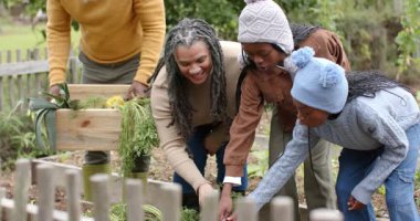 Büyükannem kökü gösterdikten sonra bahçede havuç hasadı yapan Afro-Amerikan bir aile. Aile, bahçıvanlık, hasat, açık hava, kırsal, yaşam tarzı, doğal