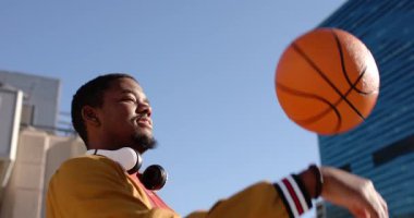 Çatıya çıkan Afro-Amerikan bir adam basketbol topunu parmağıyla döndürüyor ve Skyline 'a karşı yeteneğini gösteriyor. Şehir, faaliyet, canlı, beceri, eğlence, yaşam tarzı, modern