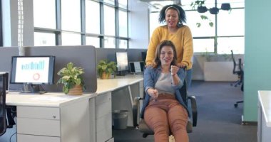 Çeşitli iş arkadaşları ellerini sandalyeye koyuyor. Eğlence olsun diye ofis masalarından dönen sandalyeyi geçiriyorlar. İşbirliği, takım çalışması, üretkenlik, canlı, modern, işyeri, neşe