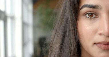 Pencereden süzülen ışık gibi gülümseyen Hintli kadın saksı, ofis sandalyesi, fotokopi odası. Portre, doğal ışık, profesyonellik, minimalizm, dinginlik, sağlık, samimiyet