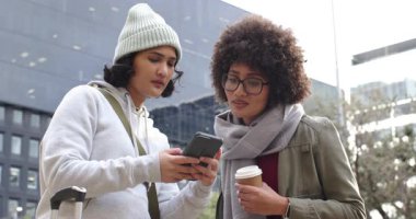 Çeşitli bayan arkadaşlar telefon sinyallerini dinliyorlar ve ellerinde bavulla kuleye bakıyorlar. Kentsel, dostluk, keşif, navigasyon, modern, gündelik, çok kültürlü