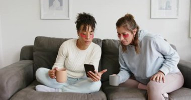 Kanepede, göz altı bandı takmış, telefonu dinleyen, bardakları yudumlayan çeşitli bayan arkadaşlar. Samimi, dostluk, rahatlama, bağlanma, samimiyet, yaşam tarzı, ahenkli