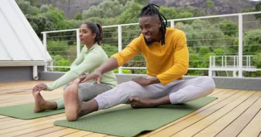 Çatı katındaki yoga minderleri üzerinde ilerleyen farklı arkadaşlar sağlığını işaret eden bir adamın üzerine. Sağlık, açık hava, rahatlama, uyum, egzersiz, rahatlık, sükunet.