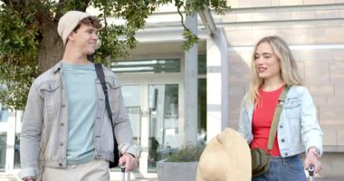 Gelen çift kapı kapı dolaşıp bavullarını çekiyor şapkalı adam dudak kremini incelemek için duruyor. Gezginler, şehir, modern, boş zaman, açık hava, keşif, gelişigüzel