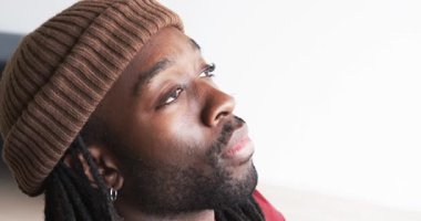 Afro-Amerikan erkek, bereli gözlerini açıyor başını eğip koltuğun minder fotokopi alanına bakıyor. Düşünce, sükunet, içgözlem, rahat, rahat, yansıma, minimalizm