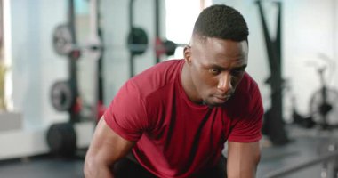 Dambıl Afrikalı Amerikalı bir adamla spor salonunda güç toplamak için sıraları eğerek sahneye çıkmak. Güç, egzersiz, fitness, kararlılık, atletizm, eğitim, motivasyon
