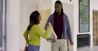 Çeşitli çiftler eve ellerinde alışveriş çantalarıyla giriyor kanepeye oturmuş telefonları boşaltıyorlar. Modern, yaşam tarzı, konforlu, çevre, rahatlama, ev dekorasyonu, çevre dostu