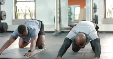 Spor salonundaki yoga minderlerinin üzerinde diz çökerek antrenörlük yapan Afrikalı Amerikalı antrenör. Zindelik, güç, dayanıklılık, egzersiz, motivasyon, eğitim, sağlık