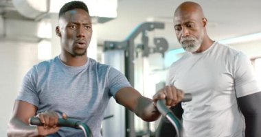Afrikalı Amerikalı erkek antrenör müşteriye, direnci ayarlamak için jimnastik salonunda pedal çevirmeye başlıyor. Antrenör, atlet, fitness, spor, egzersiz, kardiyo, yoğunluk