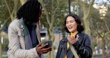 Çeşitli arkadaşlar, erkekler parkta yürürken akıllı telefonların içeriğine gülüyorlar. Gündelik, keşif, bağlantı, teknoloji, şehir manzarası, samimi, açık hava