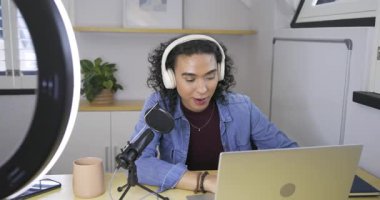 Zil ışığı, ikili olmayan bir yaratıcının mikrofona eğilip evdeki masada bilgisayara yazmasını sağlar. Teknoloji, akış, içerik, çalışma alanı, yaratıcı, modern, çevrimiçi