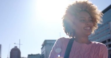 Güneş ışığı altında dönen ve gülümseyen bir kadın rıhtım güvertesinde mercek parlamaları yaratıyor, kopyalama alanı. Şehir manzarası, doğal ışık, gündelik, zarafet, modern, açık hava, yaşam tarzı