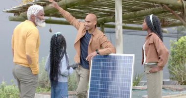 Güneş paneline yaslanan İspanyol adam pergola gölgesinin bahçedeki aileyi etkilediğini anlatıyor. Sürdürülebilirlik, yenilenebilirlik, yenilik, doğa, eğitim, açık hava, çevre