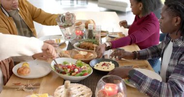Aile salatasını ahşap sunucularla kepçelemek, su dökmek, yemek masasında ekmek sepeti geçirmek. Aile, akşam yemeği, neşe, köy, ev, toplanma, günlük