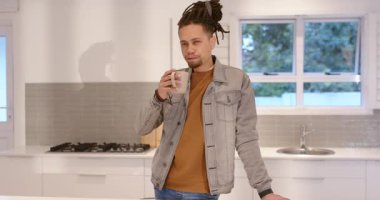 Rastalı bir adam sabah uyandığında mutfak adasındaki kupadan kahve yudumluyor. Modern, güncel, çağdaş, sağIık, rahatlama, yaşam tarzı, rahat