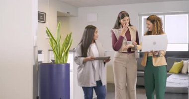 Toplantı dosyalarını gözden geçirmek, çeşitli kadın iş arkadaşlarının ofis koridorlarında dizüstü bilgisayar ve tablet kullanarak yürümesi. İşbirliği, takım çalışması, iletişim, profesyonel, iş dünyası, modern, kurumsal