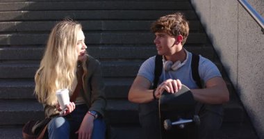 Çeşitli arkadaşlar şehir merdivenlerinde sohbet ederken kahve yudumlayıp kaykay kayıyorlar. Gündelik, dostluk, kentsel, açık hava, yaşam tarzı, modern, rahat