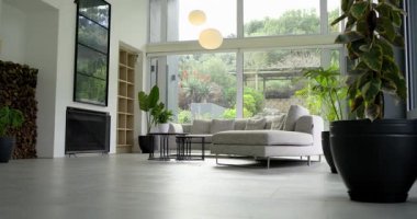 Kamera salonda alçaktan başlıyor, bölüm kanepesini, masaları, kolyeleri, bahçeyi yukarı doğru gösteriyor. İç mekan, çağdaş, minimalist, sükunet, zarafet, dekor, mimari