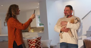 Oturma odasına giren bir çift telefon çeken bir adam kullanıyor. Yavru köpek gibi tatlı anlar paylaşıyorlar. Kopya uzayı. Samimi, samimi, yaşam tarzı, sıcak, duyarlı, evcil, çağdaş