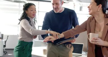 Tablet tutan adam, farklı iş arkadaşlarını teşvik ediyor, avuç içlerini birleştiriyor, kollarını kaldırıyor ve ofise sarılıyor. İşbirliği, takım çalışması, kutlama, çeşitlilik, yoldaşlık, profesyonellik, birlik