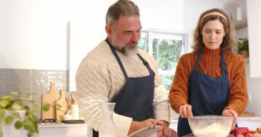 Bir çift cam karıştırma kabına yumurta kırıyor ve mutfak tezgahında hamuru çırpıyor. İşbirliği, yerli, aşçı, sıcaklık, işçilik, yaşam tarzı, kırsal