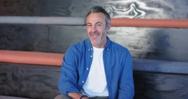 Son sınıf öğrencisi kameraya doğru dönüyor ve salondaki bankta kamera dışı yorumlara kahkahalarla gülüyor. Olgunluk, tefekkür, rahatlama, stüdyo, lüks, samimi, pozitif