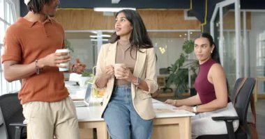 Çeşitli iş arkadaşları ellerinde kahve ve kupalarla çalışma istasyonunda dizüstü bilgisayarla tartışmalara yol açıyor. İşbirliği, çeşitlilik, gündelik, çağdaş, çalışma alanı, iletişim, takım çalışması