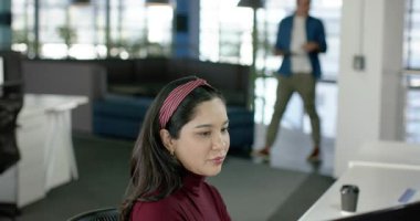 Çeşitli iş arkadaşları tablet üzerinde projeyi tartışan İspanyol bir kadının yanından geçerek içeri giriyor. İşbirliği, takım çalışması, işyeri, profesyonel, modern, iletişim, verimlilik