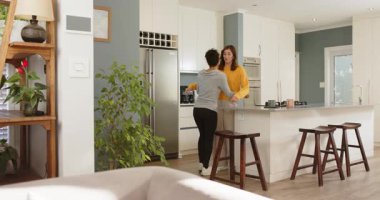 Çeşitli bayan arkadaşlar mutfağa giriyor, adada turuncu ikram ediyor ve rahatlık için arkadaşına sarılıyorlar. Arkadaşlık, sıcaklık, duygusal bağlantı, modern iç mekan, günlük yaşam tarzı, samimi, sevecen.