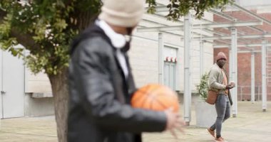 Erkek, kahve fincanı olan bir arkadaşa el sallıyor sonra da kampüste basketbol hileleri çeviriyor, fotokopi çekiyor. Gündelik, dostluk, açık hava, gençlik, şehir, dinamik, eğlence