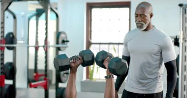 Kıdemli Afrikalı Amerikalı antrenör erkek stajyere spor salonundaki halterlerin üzerinde altıgen baskı yapıyor. Spor, güç, antrenman, sağlık, motivasyon, eğitim