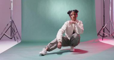 Modern stüdyo ortamında rahat bir şekilde poz veren genç bir kadın. Moda, güven, yaşam tarzı, portre, çağdaş, kentsel